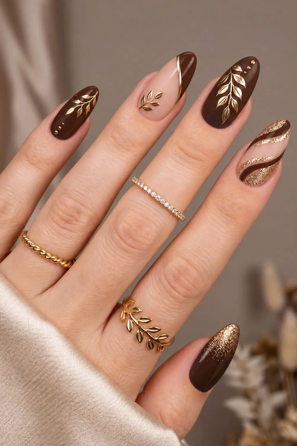 Short brown fall nails with delicate gold leaf motifs on almond tips Short brown fall nails with delicate gold leaf motifs on almond tips