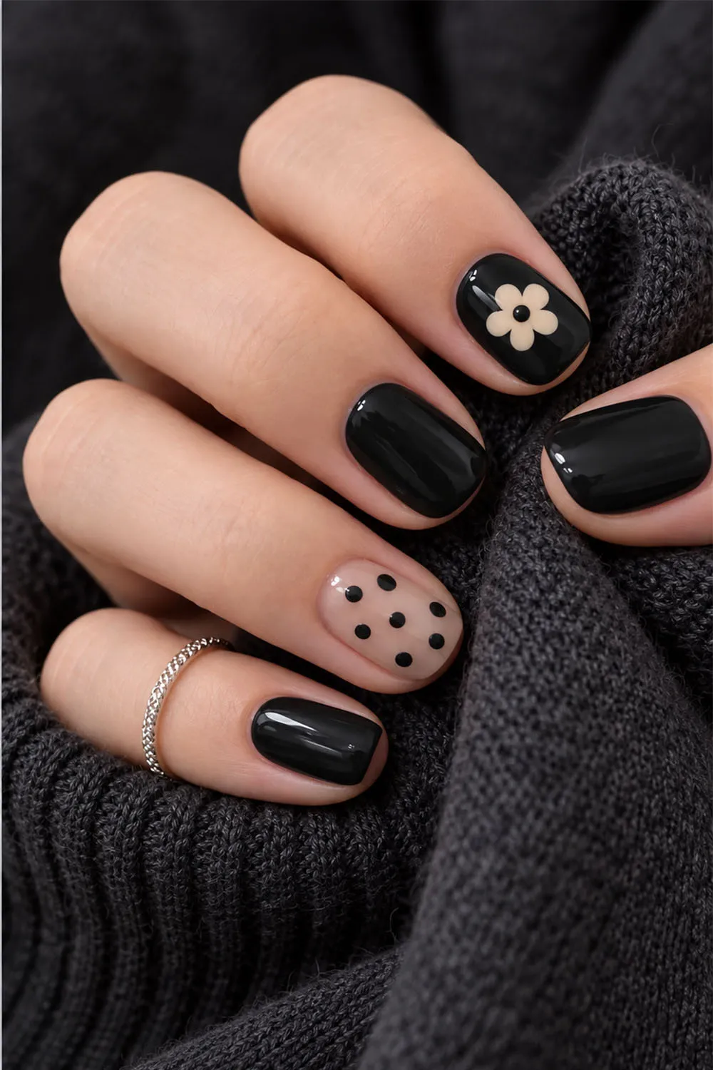 Glossy black short halloween nails with polka dots and a white daisy accent