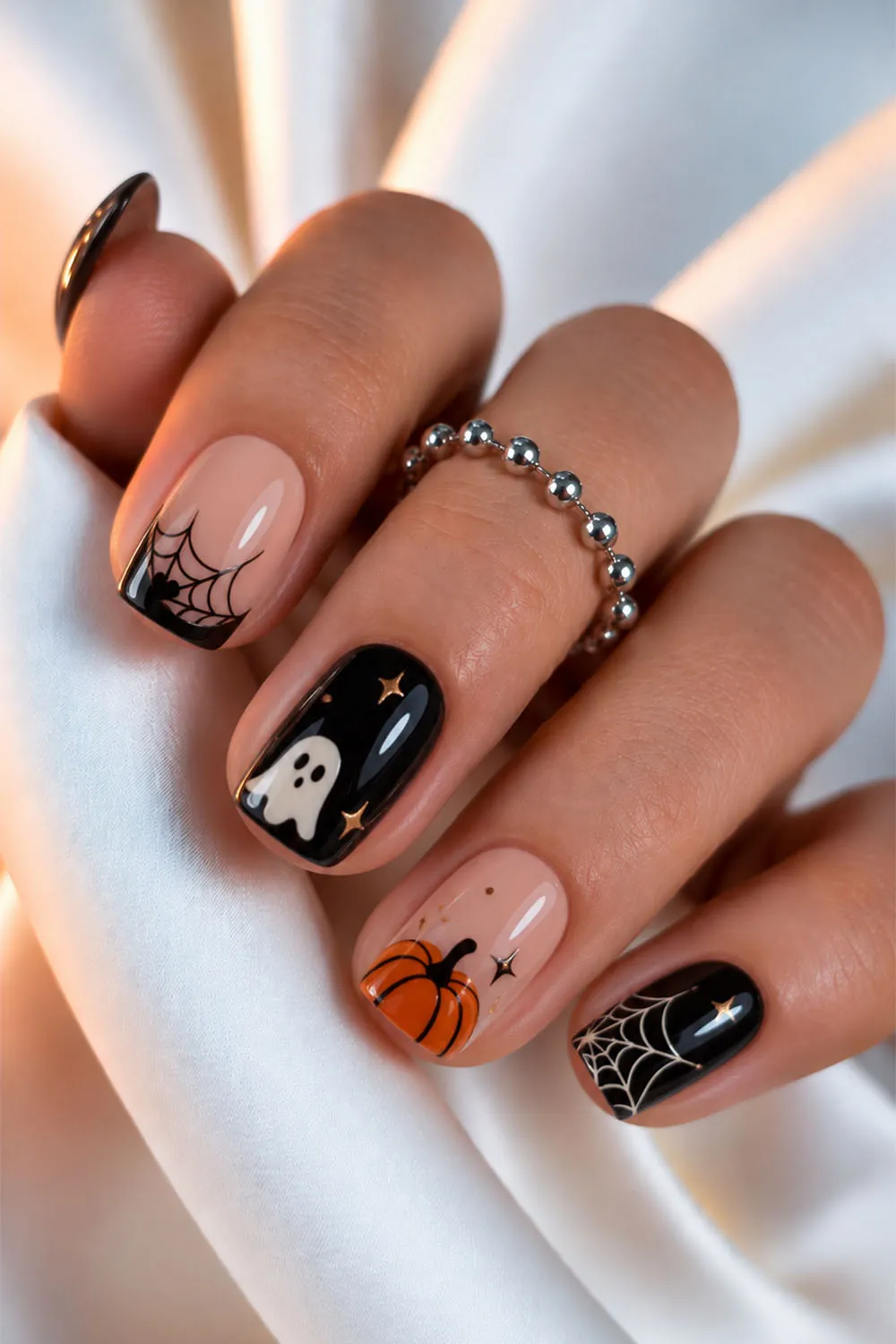 Short halloween nails with ghost, pumpkin and spiderweb art on black and nude