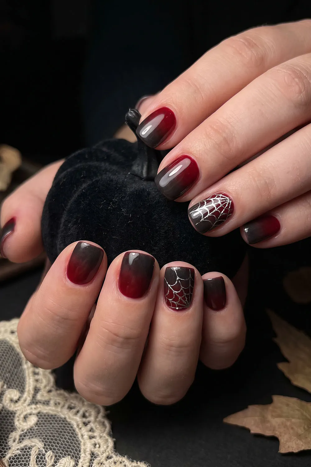 Burgundy and black ombre short halloween nails with spiderweb accents