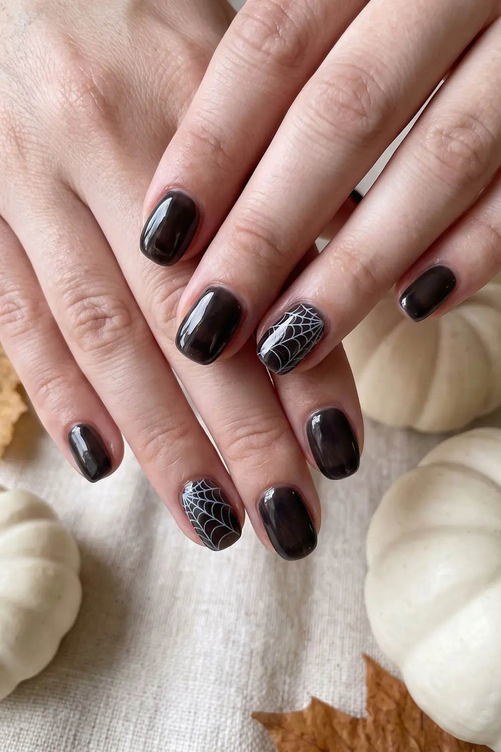 Glossy black short halloween nails with fine spiderweb accent nails