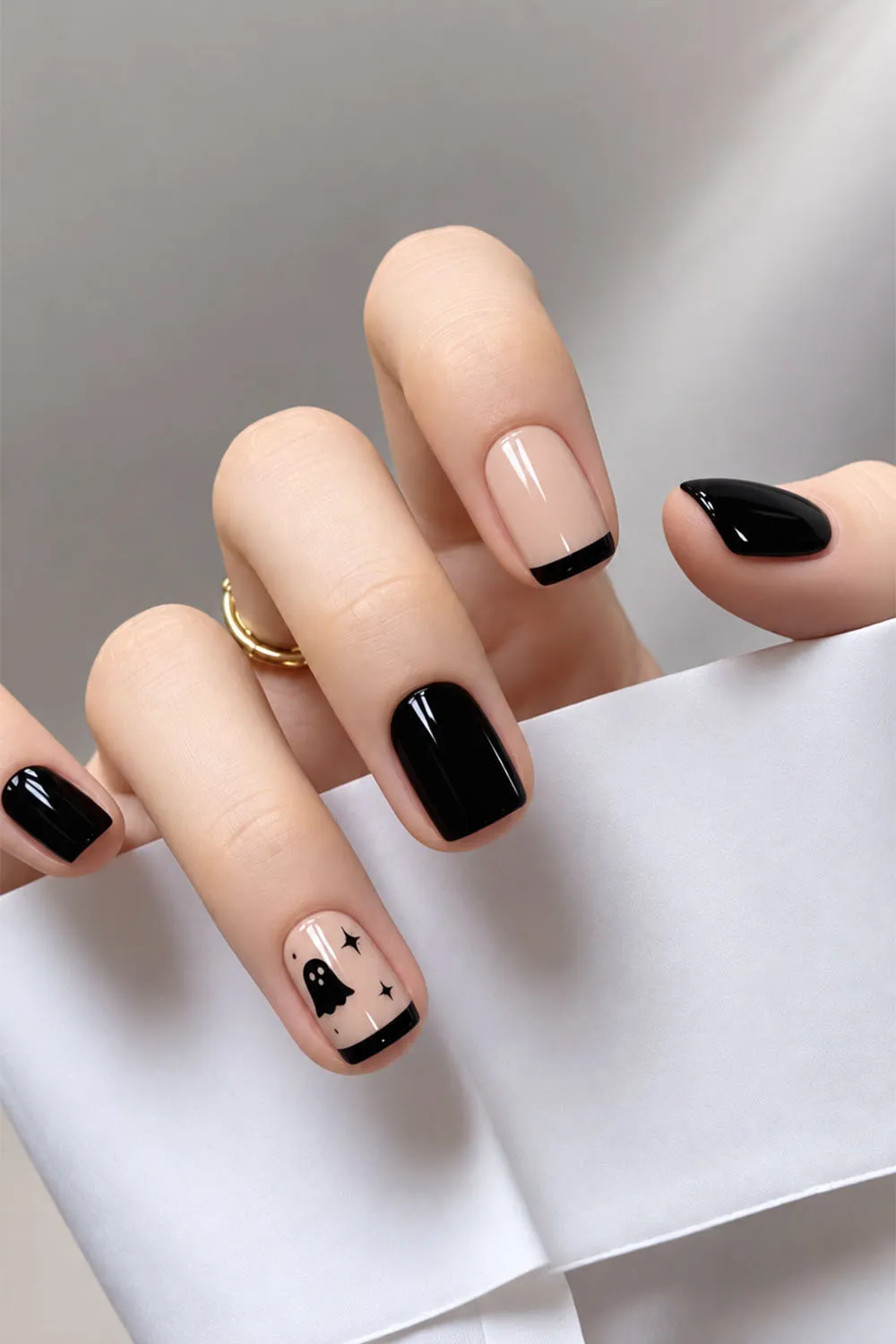 Minimal short halloween nails in nude and black with a tiny bat