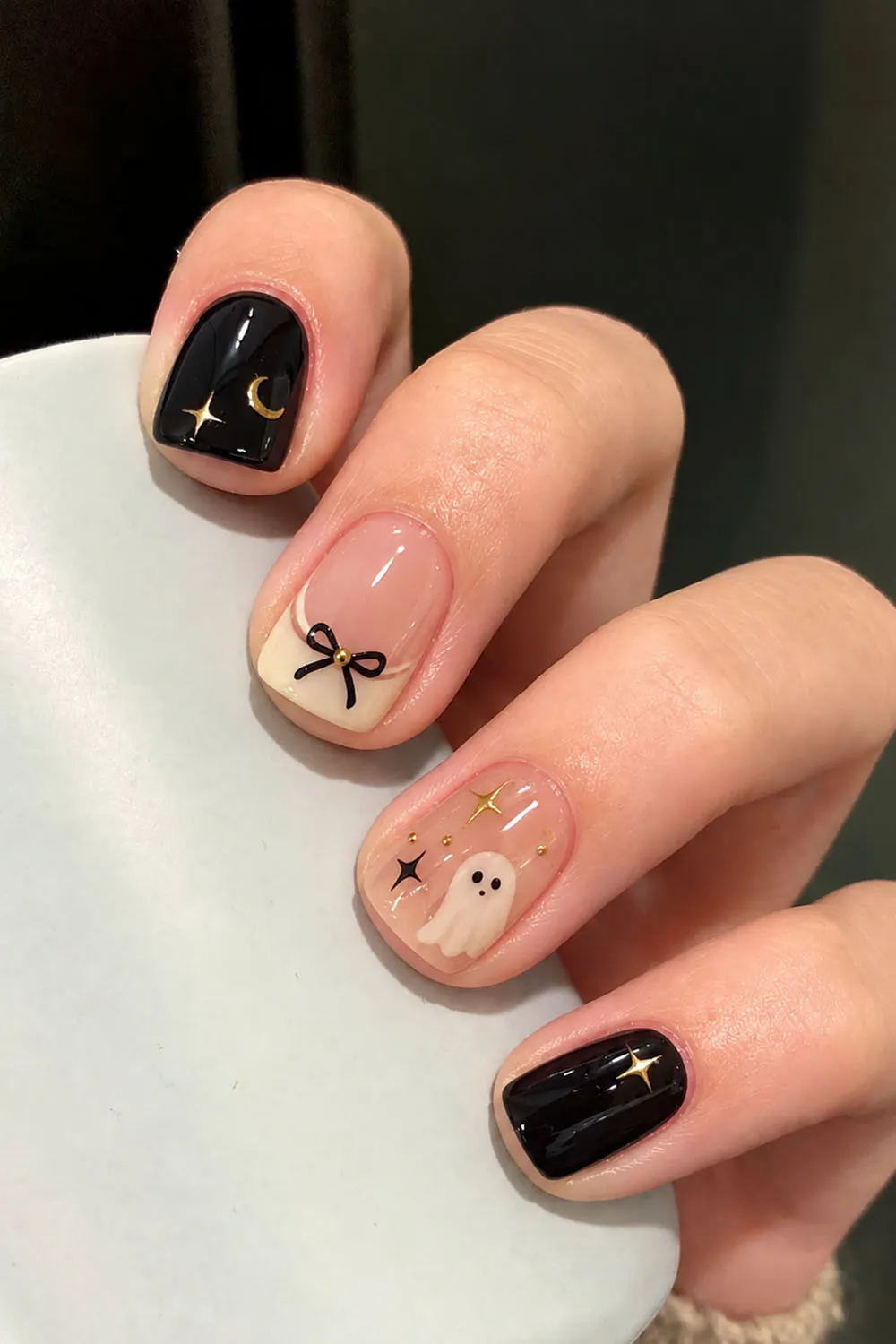 Short halloween nails in nude and black with moon, bow and ghost details
