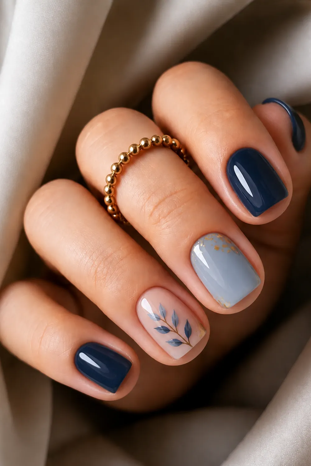 Short navy and sky blue nails with a painted leaf accent Short navy and sky blue nails with a painted leaf accent