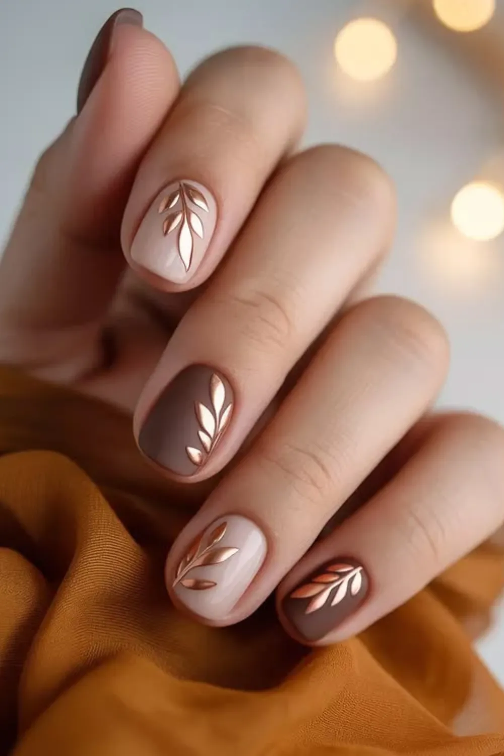 Short nude and brown nails with gold leaf designs Short nude and brown nails with gold leaf designs